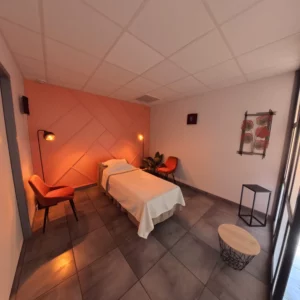 Chambre funéraire avec lit d'hommage drapé de blanc, mur d'accent rose terracotta et fauteuils en velours orange.