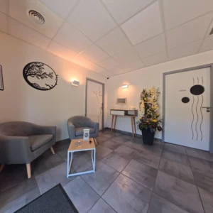 Hall d'accueil moderne de la chambre funéraire de Nogaro avec fauteuils gris, plante décorative et applique murale.