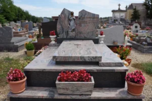 Monument funéraire sur mesure en granit rose et gris orné d'une sculpture de la Vierge Marie et de bacs de fleurs.