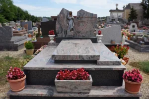 Monument funéraire sur mesure en granit rose et gris orné d'une sculpture de la Vierge Marie et de bacs de fleurs.