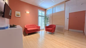 Salon funéraire privé et intimiste aménagé avec canapé et fauteuils rouges pour le recueillement des familles.